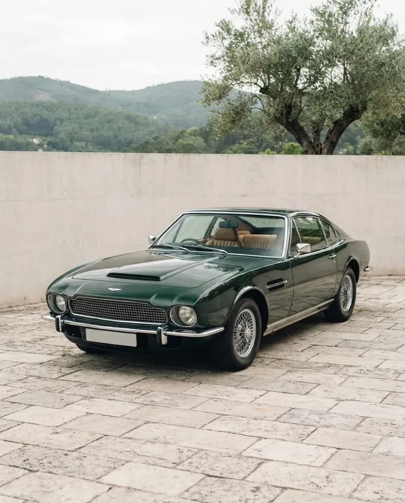 Um grand tourer clássico verde-escuro num pátio de muros de pedra no campo de Sintra